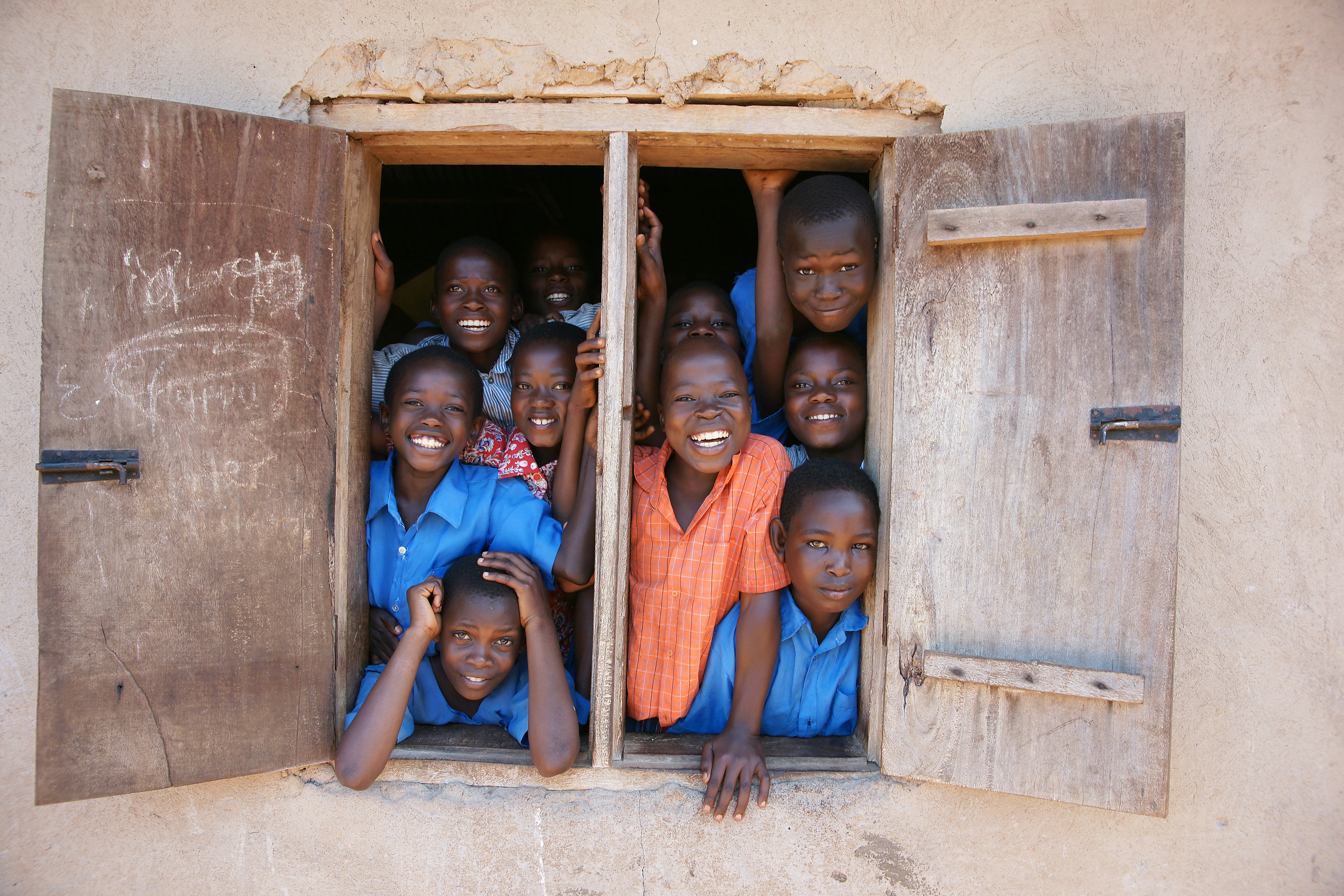 Children smiling through a window frame.